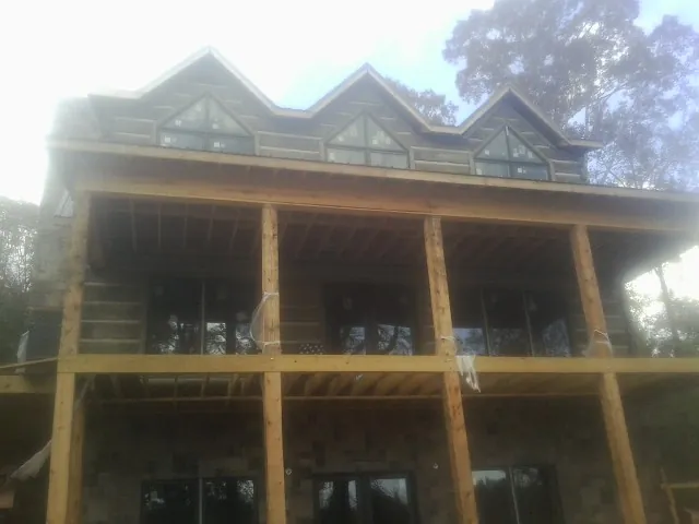 Dormers and porch framing on a large log home under construction — Roof Coating work by our crew in Royal Center
