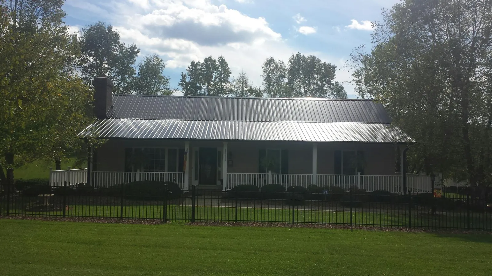 Gray metal roof on a brick ranch with a full width front porch — Gutter Guard Installation work by our crew in Royal Center