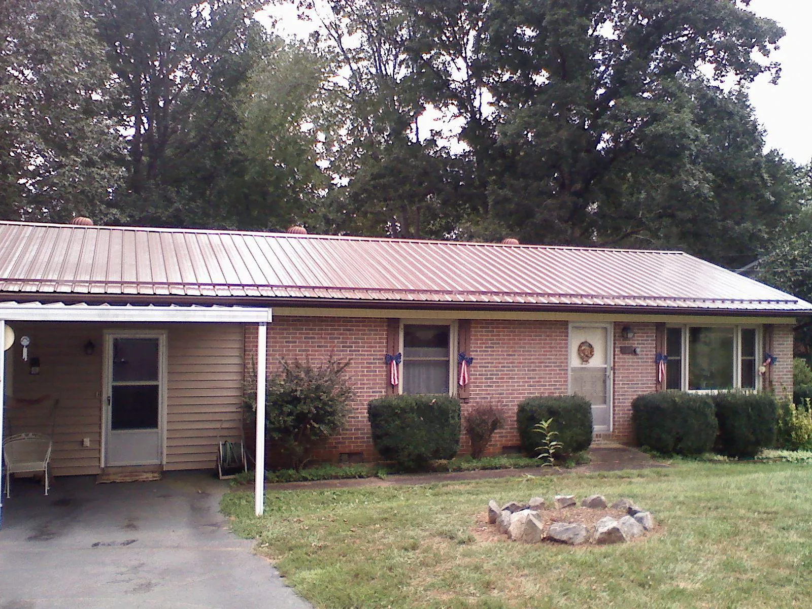 Bronze metal roof and carport on a brick ranch home — Roof Repair work by our crew in Royal Center