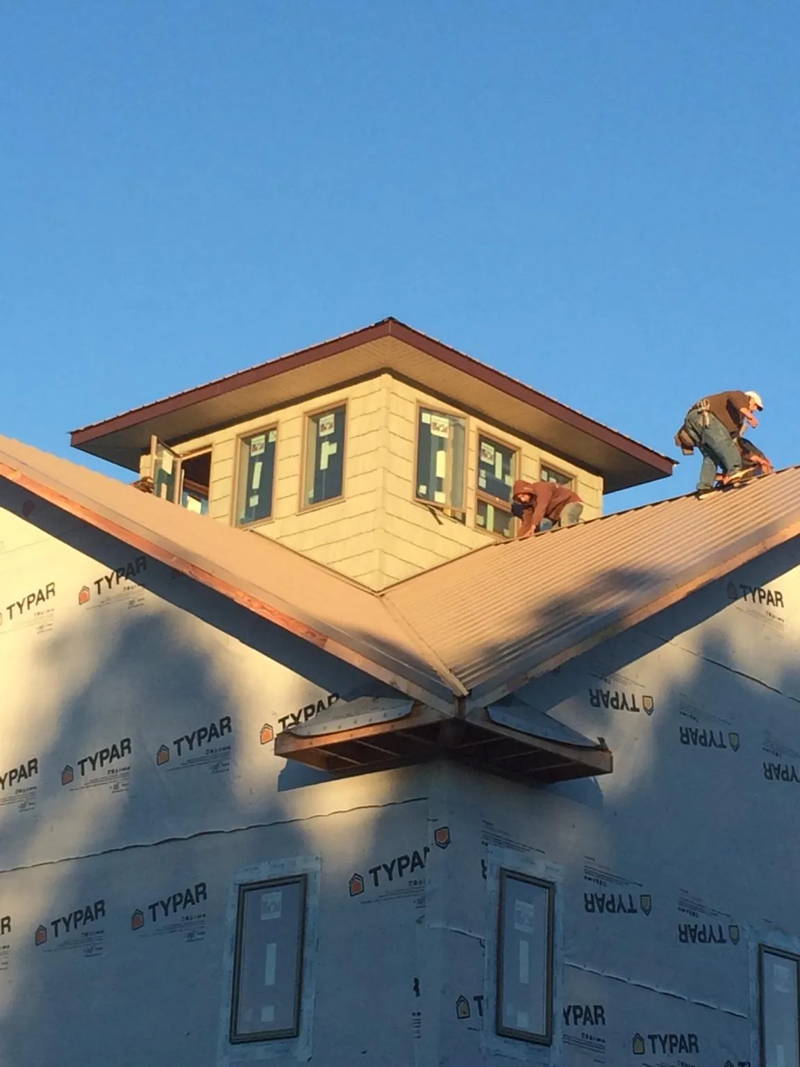 Roofers working around a rooftop cupola on a new metal roof at sunset — Roof Waterproofing in Royal Center by Roofing Brothers